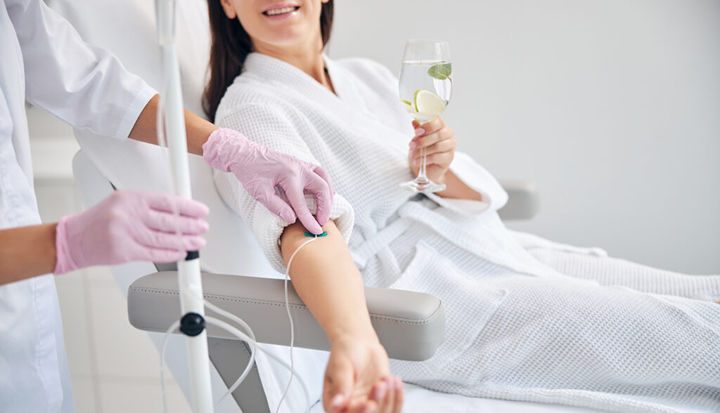 Cropped photo of a woman with a glass of drink sitting in a cosmetic chair